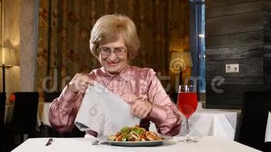 退休妇女坐在餐馆里，桌上放着蔬菜沙拉和一杯新鲜水果饮料。 她70多岁的高级模特